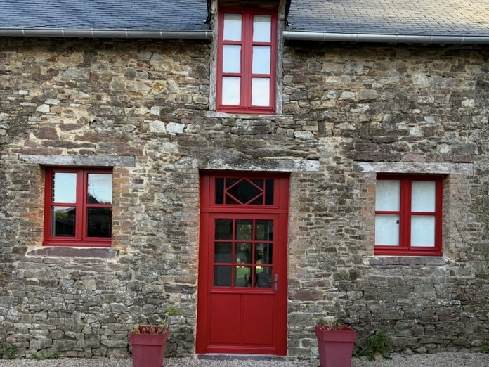 Maison en pierre avec porte et fenêtres bois rouges