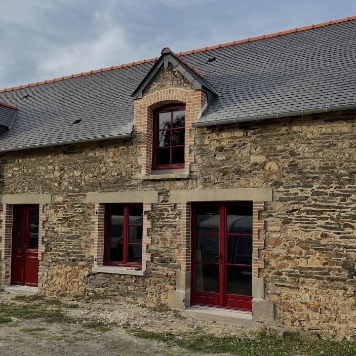 Maison en pierre avec fenêtres en bois rouge